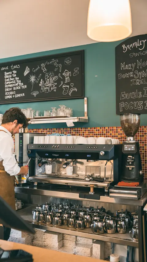 A barista at the coffee machine beneath the chalkboards