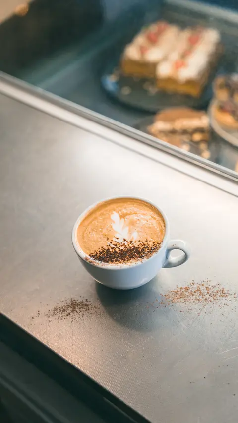 A cappuccino served beside the cake counter