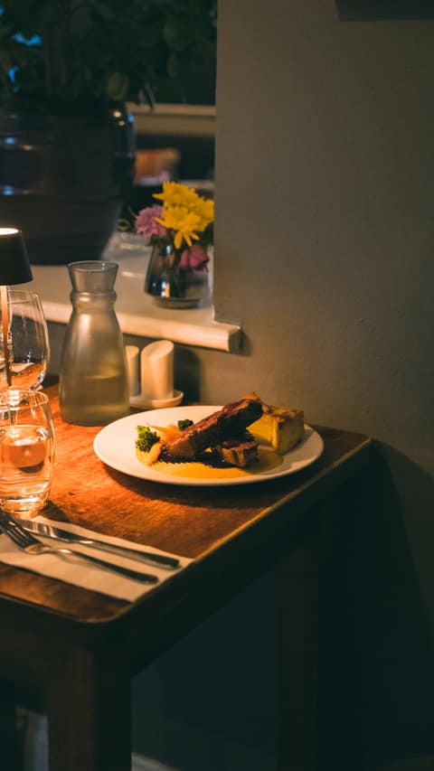 An evening main with vegetables and potatoes beside a vase of flowers