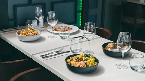 A spread of dishes and glasses on a table by the bar
