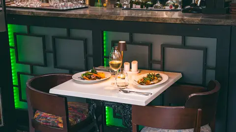 A table for two set beneath the green-lit panelling in the evening dining room