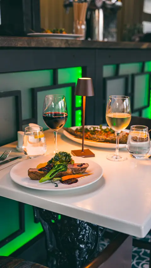 An evening table for two with red and white wine, candlelight and the duck and fish mains