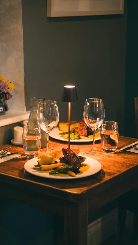 Two plated dinners with vegetables and potatoes on a softly lit table