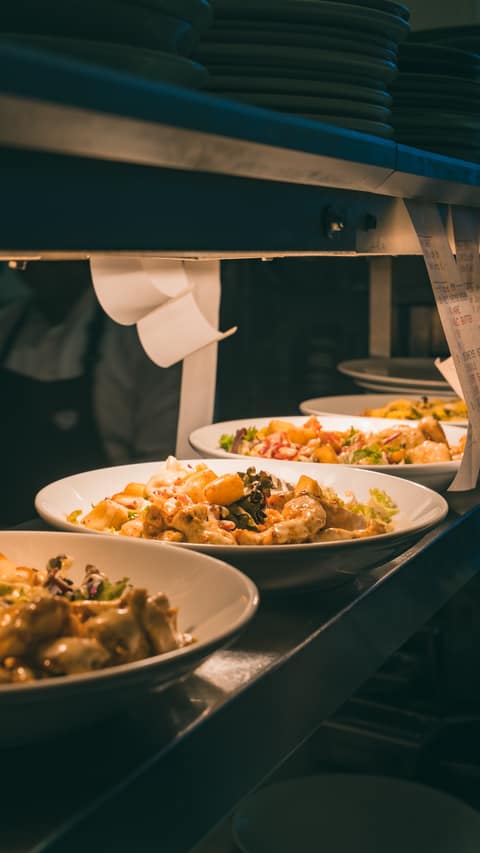 Freshly prepared salad bowls lined up on the kitchen pass