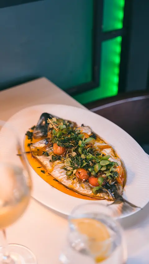 The whole grilled fish with a glass of white wine, seen from above
